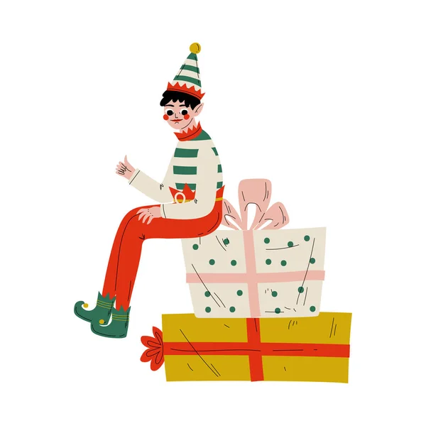 Рождественский эльф персонаж сидит на подарочных коробках, милый мальчик Санта-Клаус Помощник векторной иллюстрации — стоковый вектор