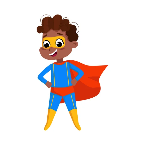Carino ragazzo afroamericano in costume da supereroe blu e cappuccio rosso, adorabile supereroe bambino in piedi con le mani sulla sua vita personaggio cartone animato stile vettoriale Illustrazione — Vettoriale Stock