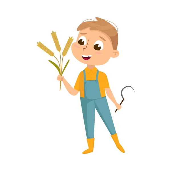 Aranyos fiú gazdaság sarló és Sheaf of Spikelets a kezében, Kid Farmer karakter overallban dolgozik Farm Cartoon Style Vector Illusztráció — Stock Vector