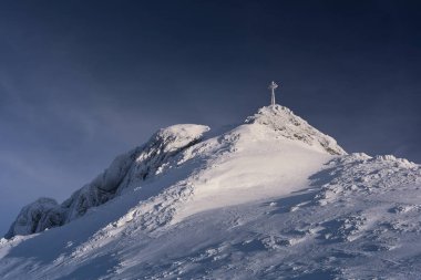 Snow covered cross on the mountain top Giewont. clipart