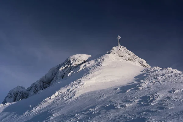 Karla kaplı dağın tepesinde Giewont çapraz.