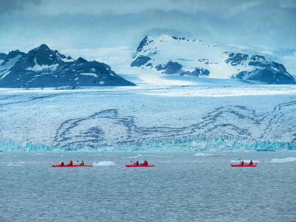 En grupp turister i röda kajaker nära Jokulsarlon Glacier — Stockfoto