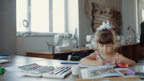 Pequena menina bonita em desenha com marcadores coloridos na mesa no quarto — Vídeo de Stock