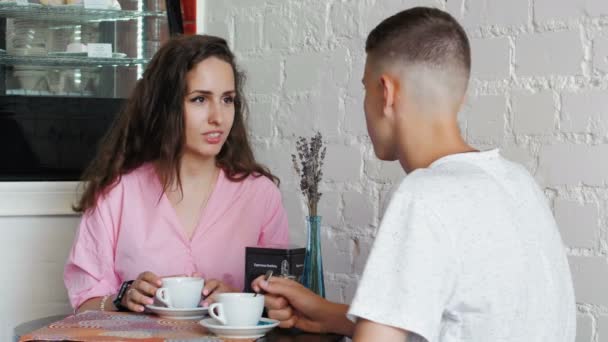 Kvinnan gör en Nfc-betalning. Datum för ett ungt par på café — Stockvideo