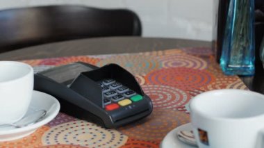 Kafedeki genç adam bedelini akıllı bir telefon ve terminal kullanarak ödüyor.