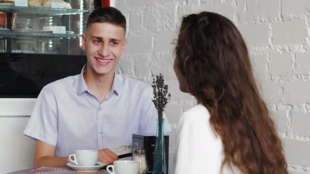 青シャツの男は、payning カフェで法案の Nfc 技術とカードを使用します。カフェで若いカップルの日 — ストック動画