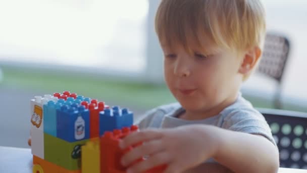 男孩玩汽车从彩色方块在桌子上 — 图库视频影像