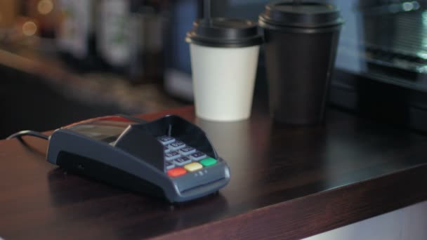 Hombre joven en la cafetería está pagando el precio mediante el uso de un teléfono inteligente y terminal — Vídeos de Stock