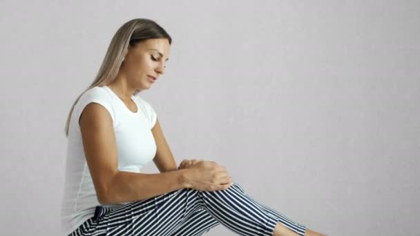 Frau reibt sich im Reha-Zentrum das schmerzende Knie — Stockvideo