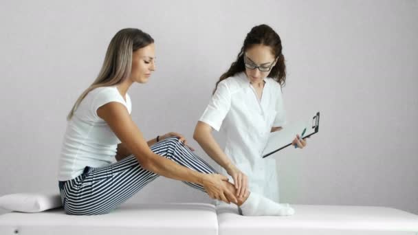Médico examina las mujeres pierna en la clínica — Vídeos de Stock