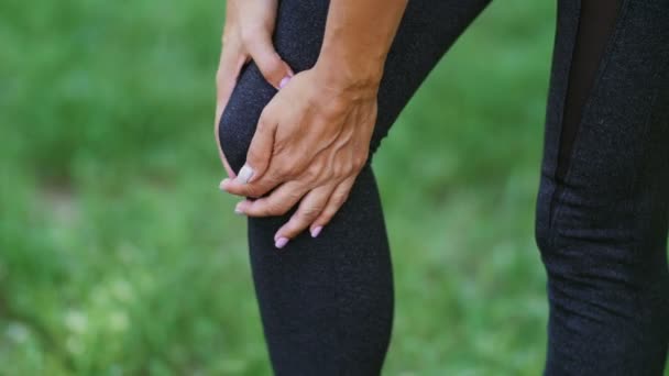 Mujer en polainas negras masajea su rodilla enferma — Vídeos de Stock