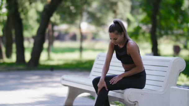 Kadın bankta oturur ve hastalıklı diz masajlar — Stok video