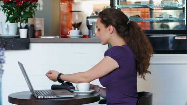 Vrouw maakt een Nfc betaling en drinken koffie — Stockvideo