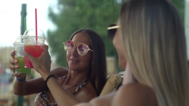 Mulheres felizes em óculos de sol desfrutando de uma bebida na bela praia — Vídeo de Stock