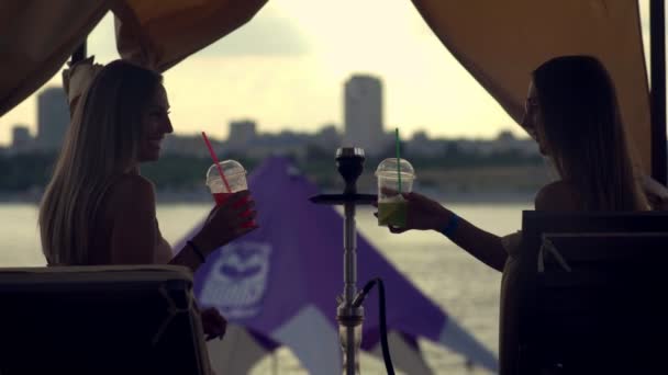 Frauen rauchen Wasserpfeife und schlagen am Strand einen Cocktail — Stockvideo