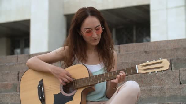 Vrouw speelt akoestische gitaar op de trap — Stockvideo