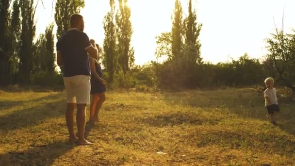 Niño mira burbujas de jabón en el parque por los padres — Vídeo de stock