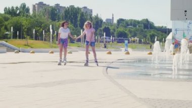 İki genç kız parkta paten kayıyor..