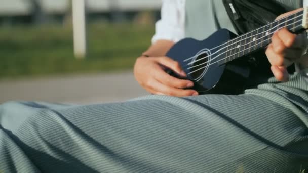 Genç bir kadın ukulele çalıyor, izin günlerinde gitar çalıyor. — Stok video