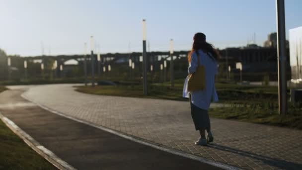 Femme hipster marchant dans le parc pendant le coucher du soleil — Video