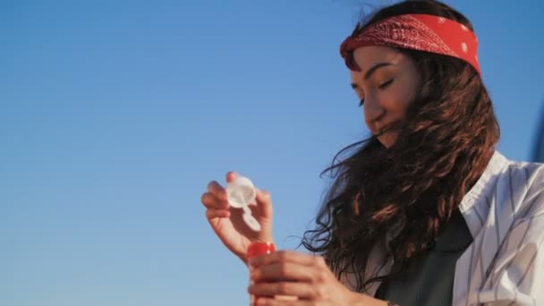 Женщина весело дует пузырь, голубое небо на заднем плане — стоковое видео