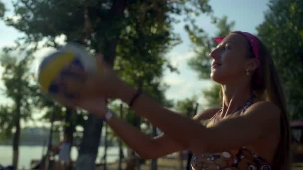 Счастливая женщина играет в волейбол на пляже — стоковое видео