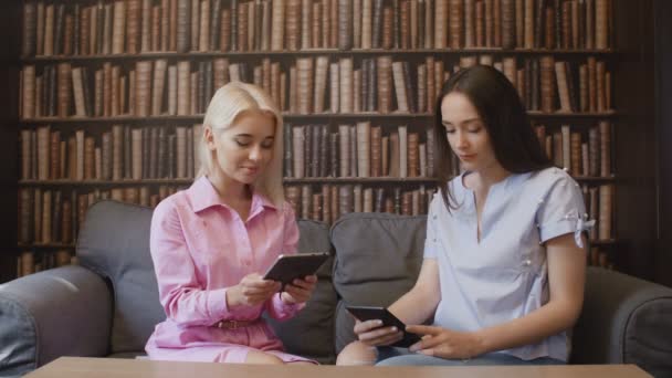 Las mujeres jóvenes están leyendo libros electrónicos — Vídeo de stock