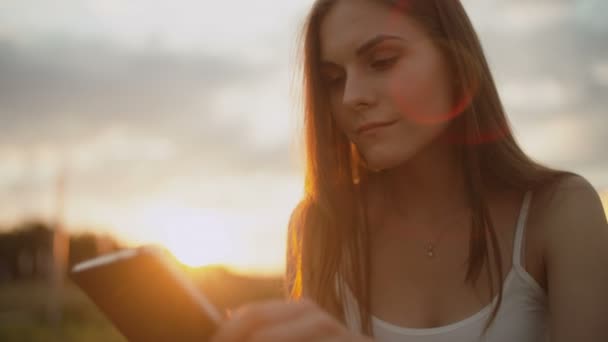 Νεαρή γυναίκα στο πάρκο διαβάζει e-book, ηλιοβασίλεμα στο ανάχωμα — Αρχείο Βίντεο
