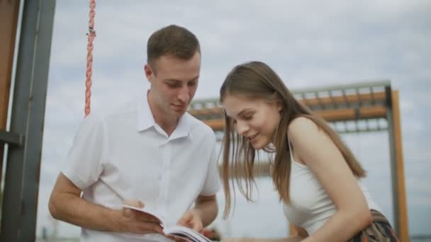 Un paio di studenti stanno leggendo un libro nel parco. rallentatore — Video Stock