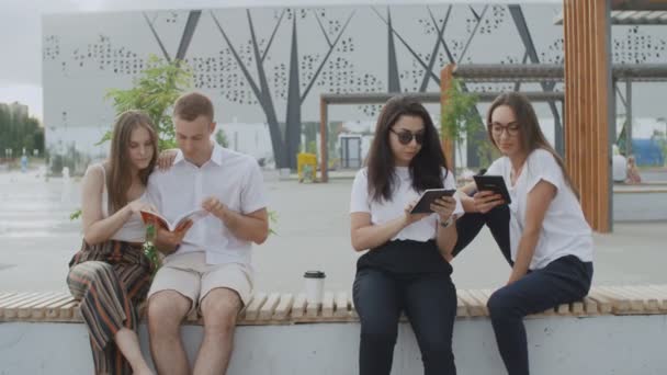 Студенты читают книгу в парке — стоковое видео