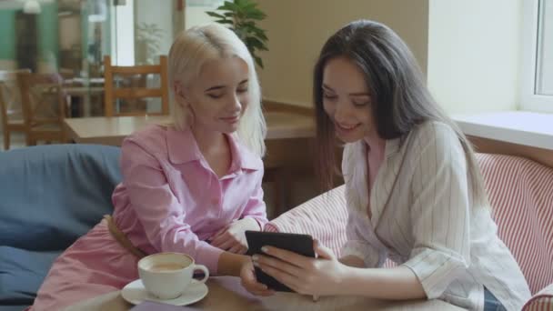 Chicas en un café leyendo un libro divertido . — Vídeo de stock