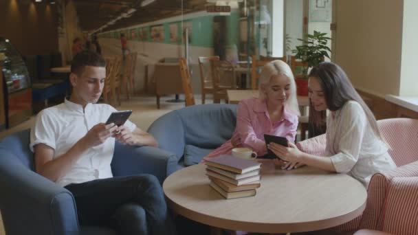 Studenci czytają ebooki w kawiarni. — Wideo stockowe