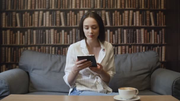 Schöne Frau liest Buch im Café — Stockvideo
