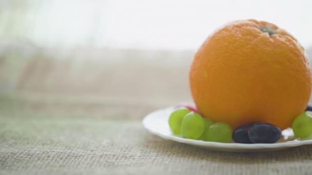 Naranja y uvas en plato — Vídeo de stock