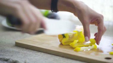 Şef sarı biber dilimlerini kesiyor. Yavaş çekimde yakın çekim.