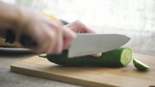 Жінка ріже огірок на кухні — стокове відео