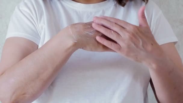 Зрелая женщина увлажняет руки кремом — стоковое видео