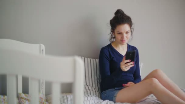 Mujer compras en línea en su cama mediante el uso de su teléfono — Vídeo de stock