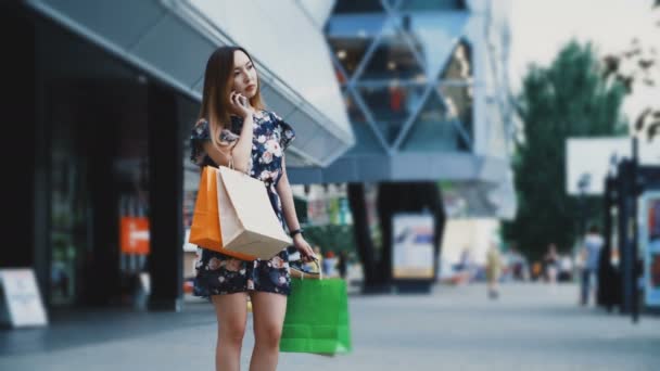 Frau mit Einkaufstasche bestellt Taxi in der Nähe eines Einkaufszentrums — Stockvideo