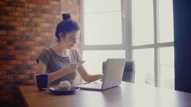 Çevrimiçi alım yapan genç bir kadın evde banka kartı kullanıyor