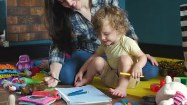 Anne ve kızı yere bir defter çiziyor.