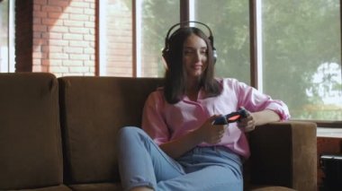 Kulaklıklı genç bir kadın oyun oynarken joystick kullanıyor.