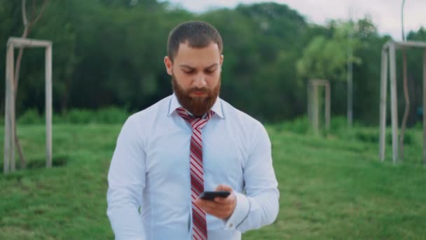 Atractivo hombre de negocios mirando en el teléfono móvil, sintiéndose feliz, viendo buenas noticias . — Vídeo de stock