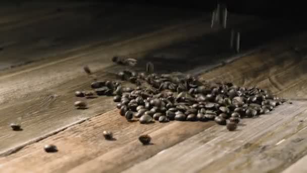 Кофейные зерна падают на деревянный стол — стоковое видео