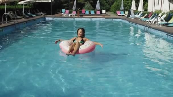 La mujer está flotando con un círculo inflable de la dona en la piscina swomming — Vídeos de Stock