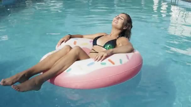 Mujer alegre atractiva está flotando con un círculo inflable de la dona en la piscina swomming — Vídeos de Stock