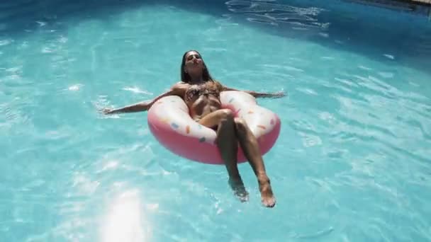 Mujer es relajante en inflable rosado donut float en piscina — Vídeos de Stock