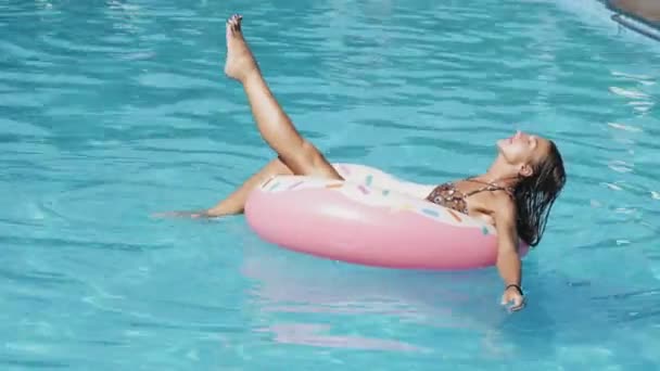 Sexy mujer atractiva está nadando en el anillo de goma inflable en la piscina.v — Vídeos de Stock