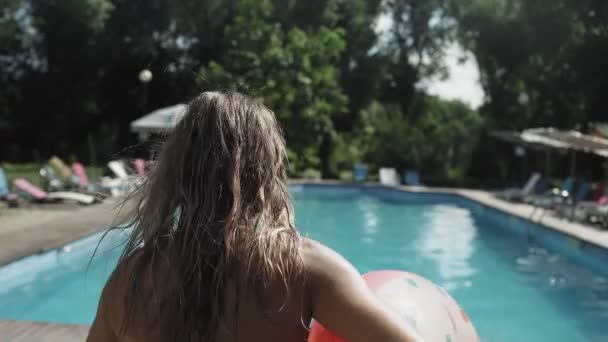 Mujer joven con anillo de goma inflable en las vacaciones de verano saltando en el agua clara de la piscina azul — Vídeos de Stock