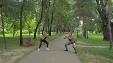 Spor kıyafetli kadınlar dışarıda Squats egzersizi yapıyorlardı. Fitness Kadın Parkta Çalışıyor